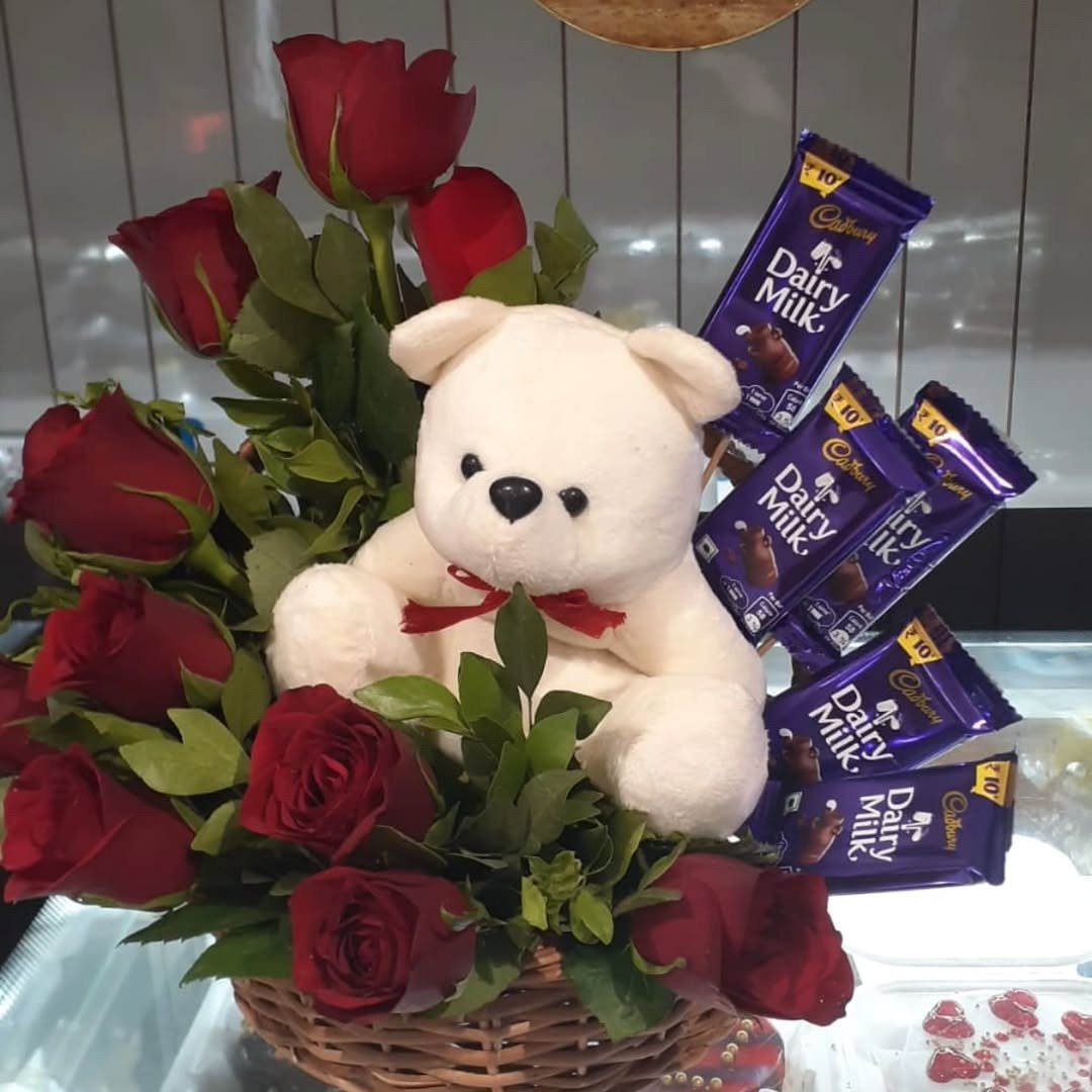 Basket with red roses, teddy bear and chocolate bars