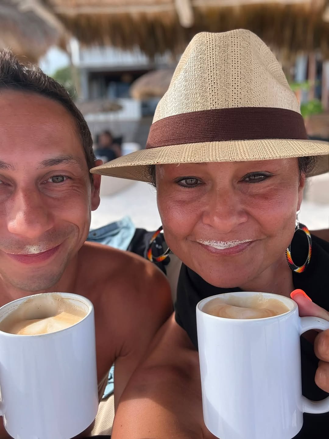 Smiling couple taking a selfie, each holding a coffee mug