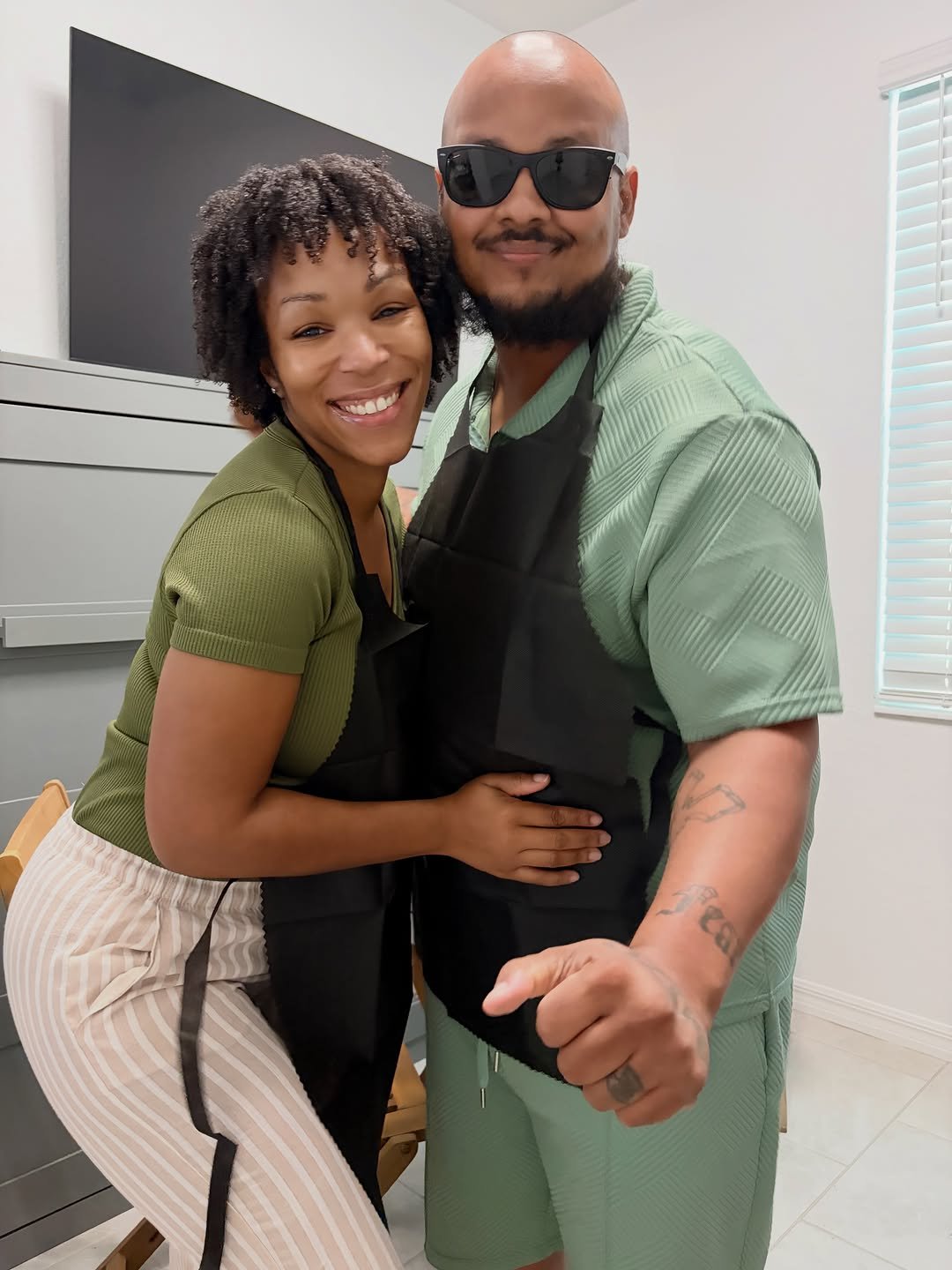 Beaming woman leaning against her husband at an at-home paint and sip date