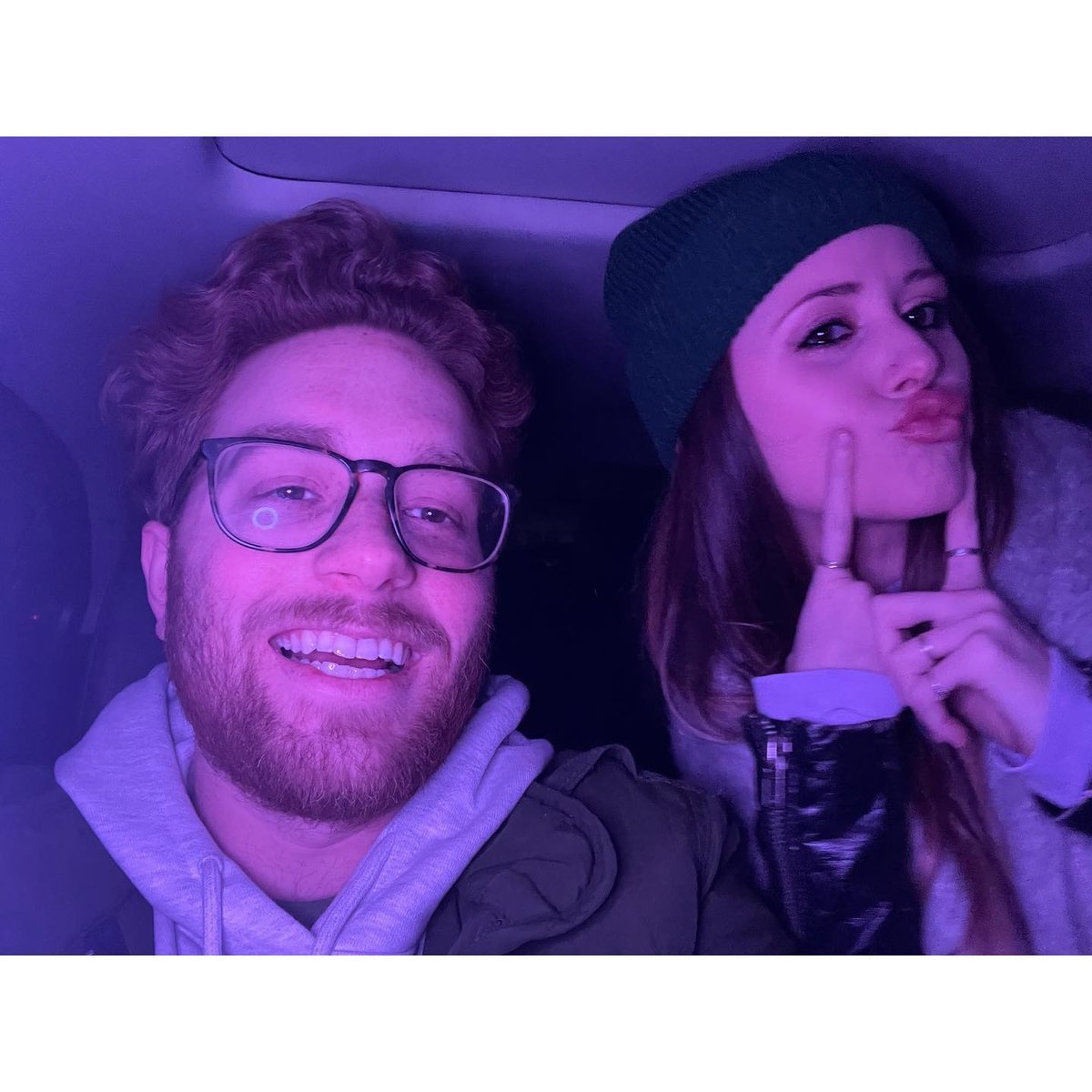 Couple taking a playful selfie together in a car at night