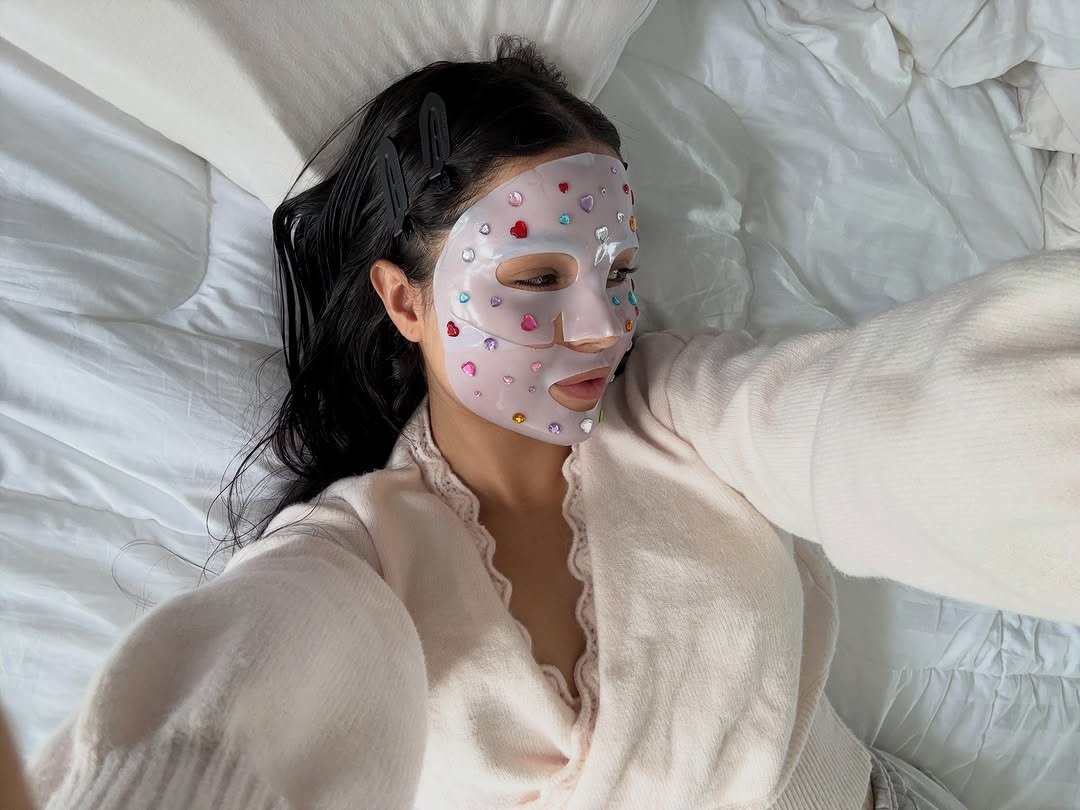 Woman in bed wearing sheet face mask and robe