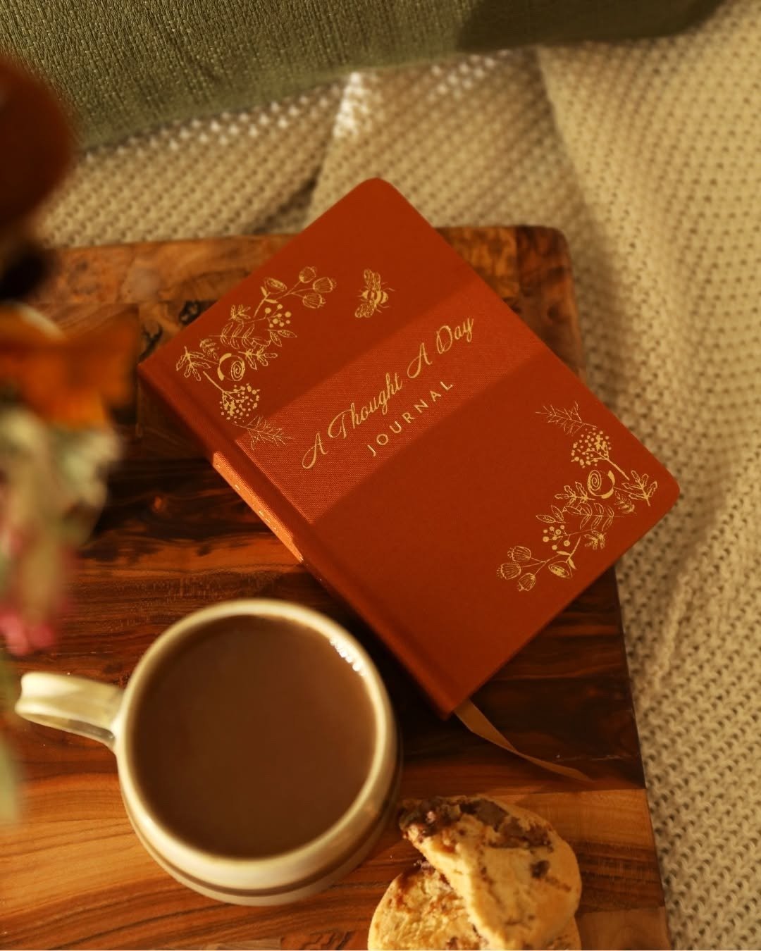 Journal and warm drink on wooden board in cozy corner