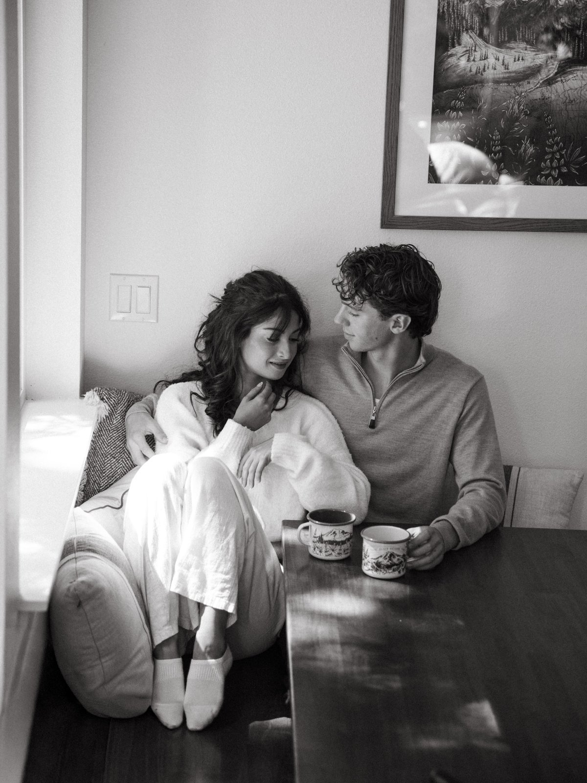 Black and white photo of a couple talking at a table with coffee mugs