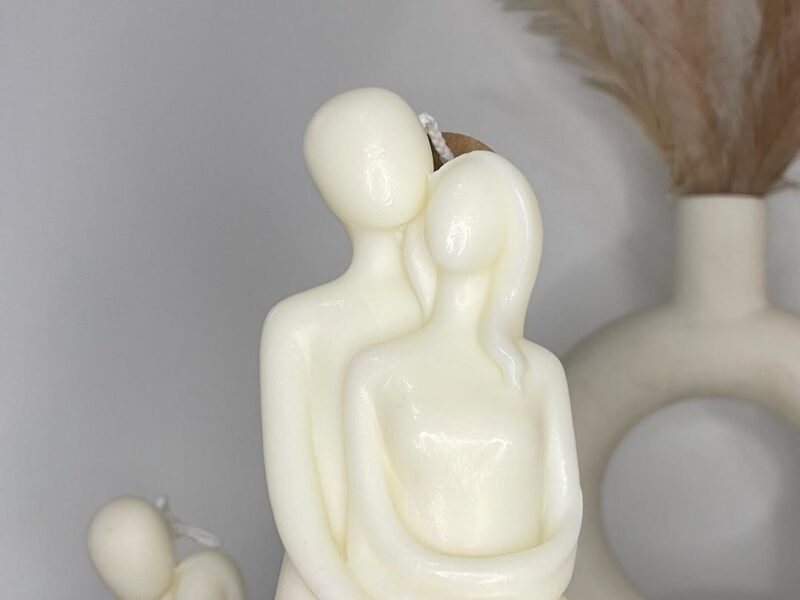 Hand holding a romantic couple-shaped white scented candle