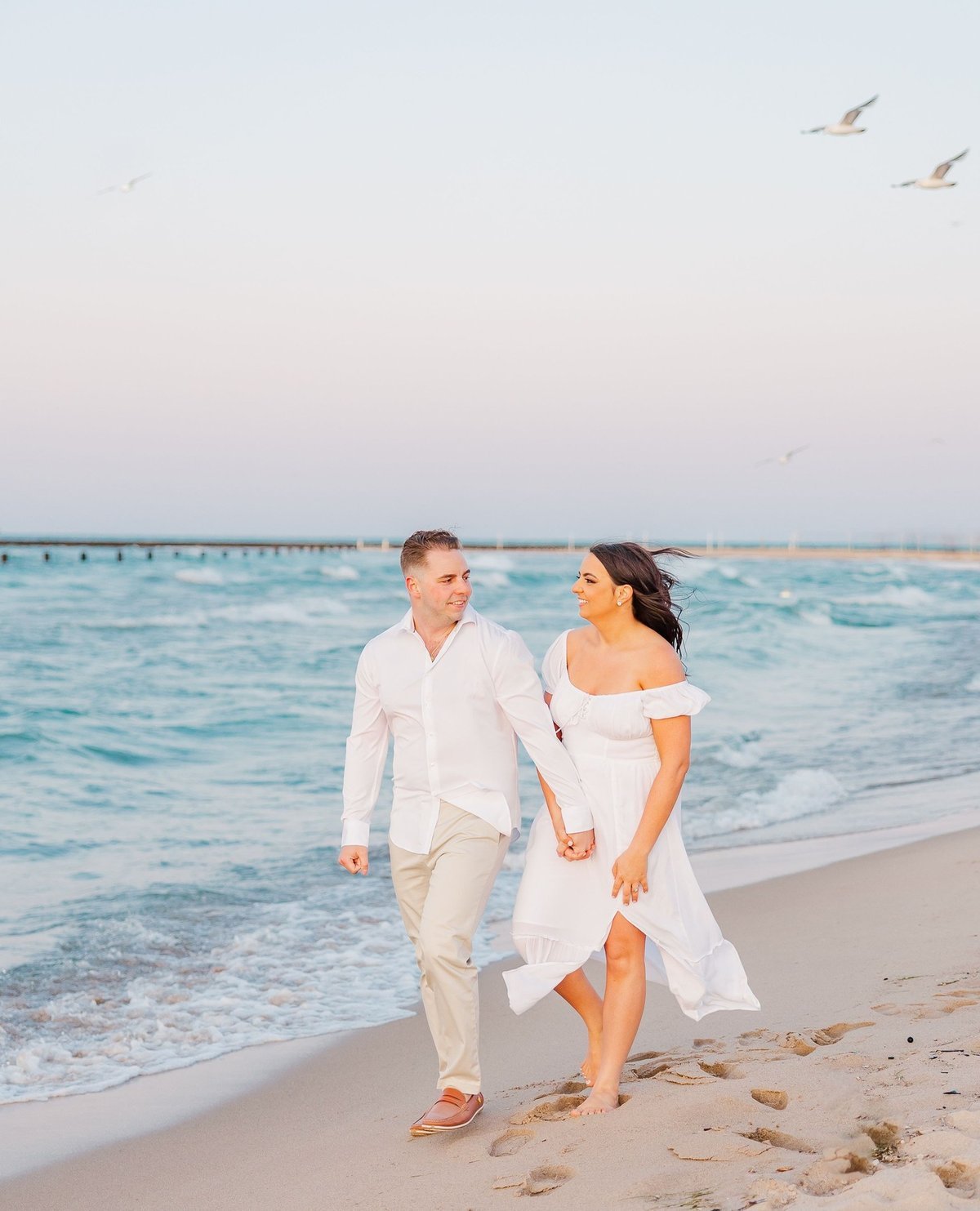 Couple walking on a beach at the water edge, talking