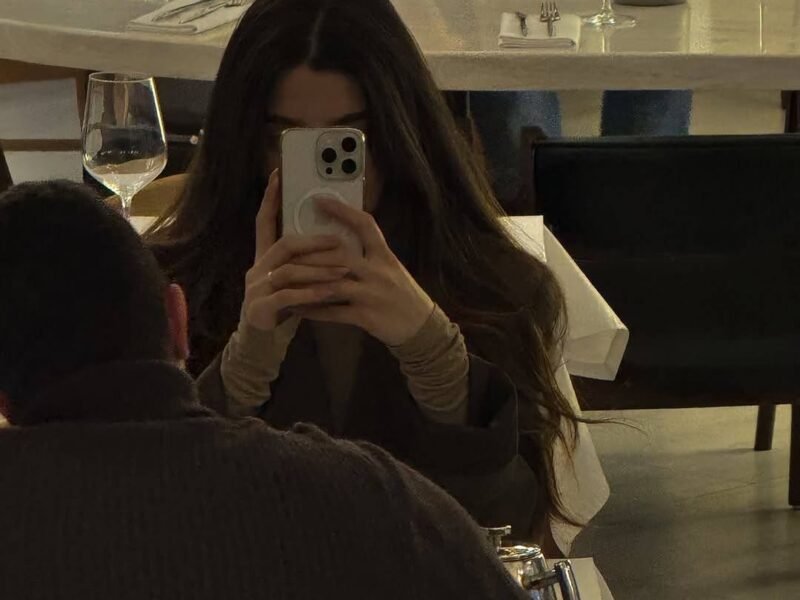 Woman absorbed in smartphone at restaurant dinner table, date across from her