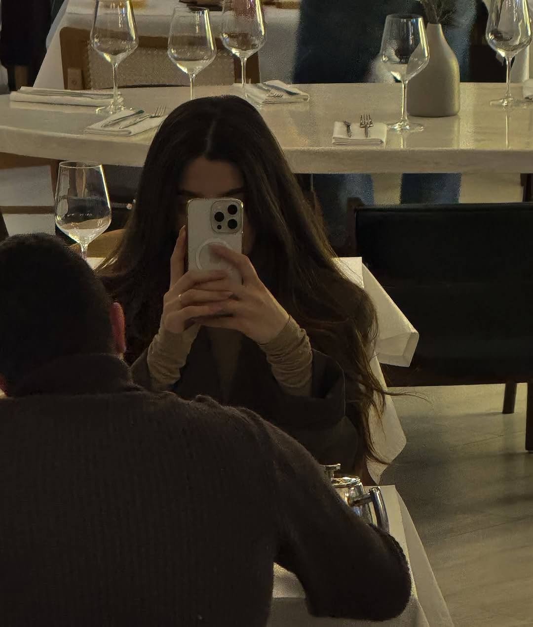 Woman absorbed in smartphone at restaurant dinner table, date, from our date night mistakes guide