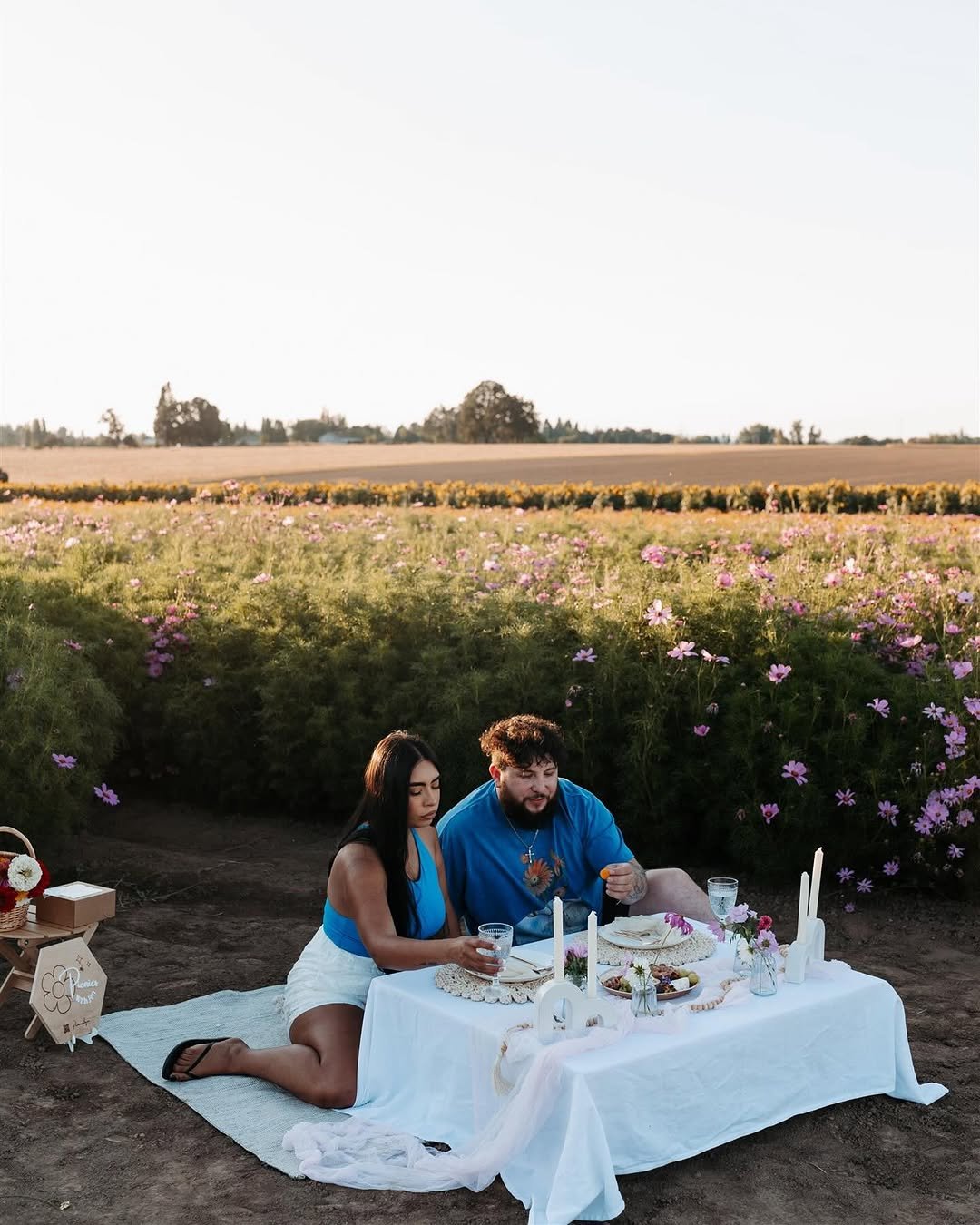 Couple enjoying romantic picnic date night at flower field at sunset