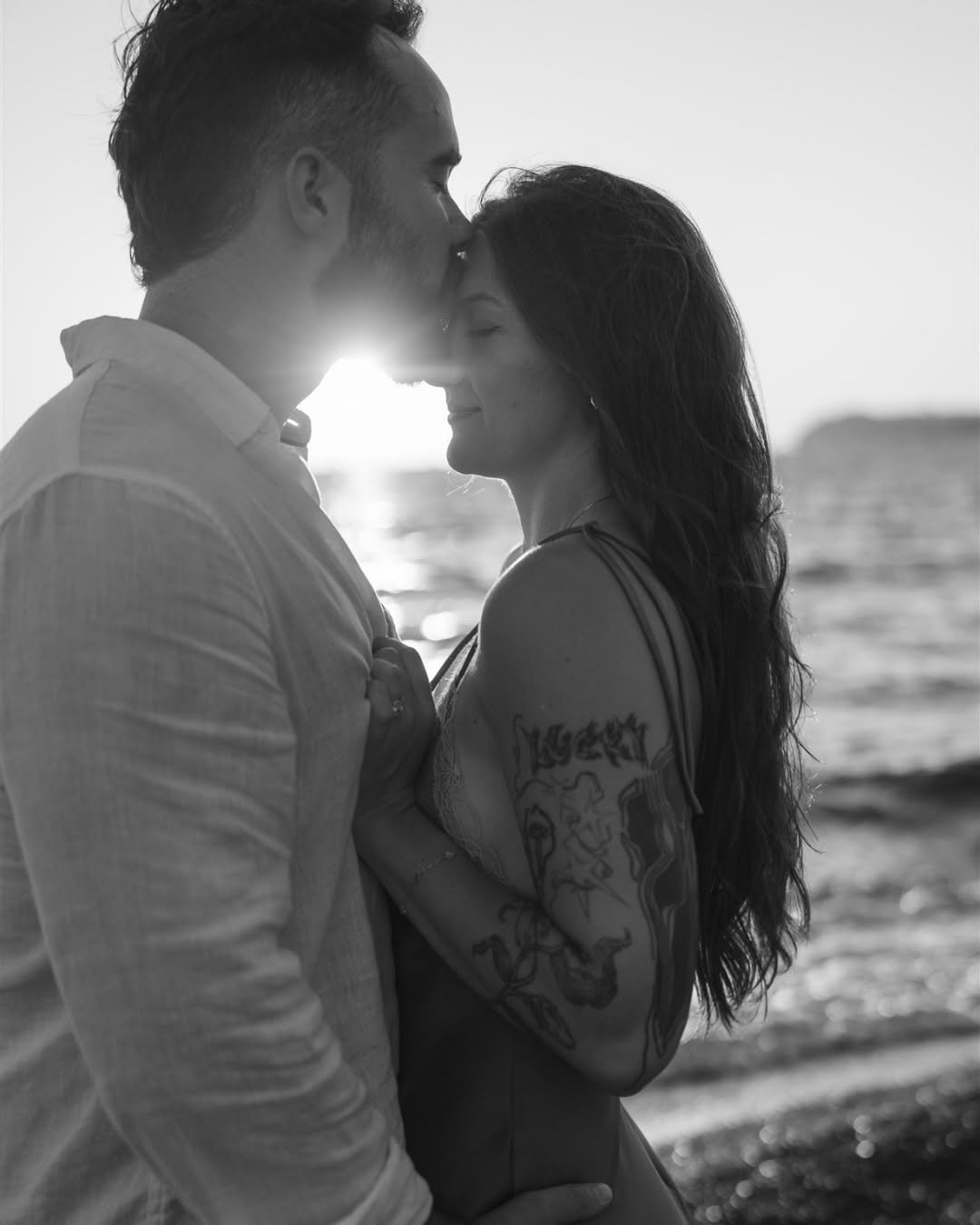 Black-and-white close-up of couple in tender embrace at sunset on beach