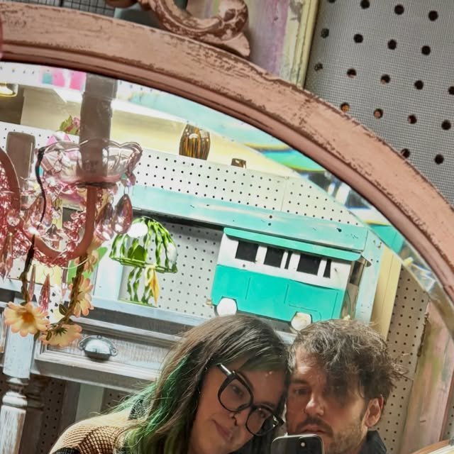 Couple taking a mirror selfie in a thrift store