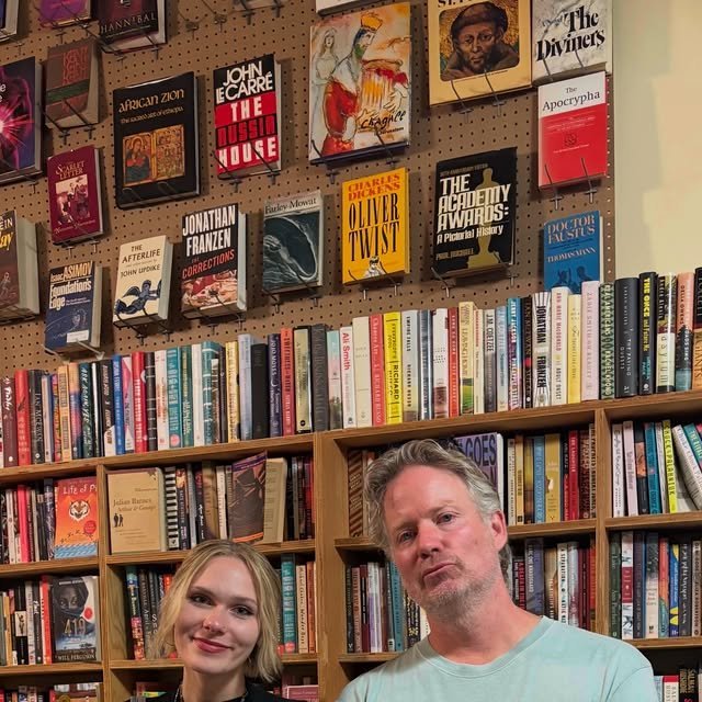 Couple with coffee browsing books in a cozy used bookstore
