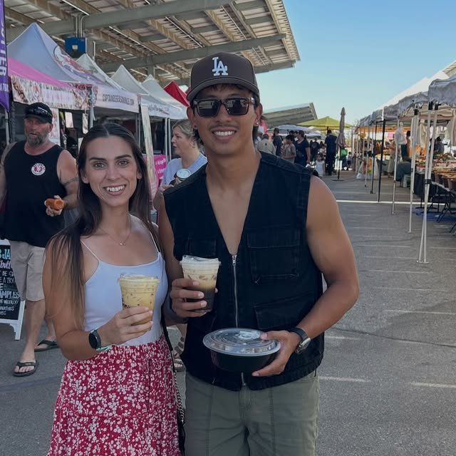 Couple enjoying drinks and food at an outdoor farmers market