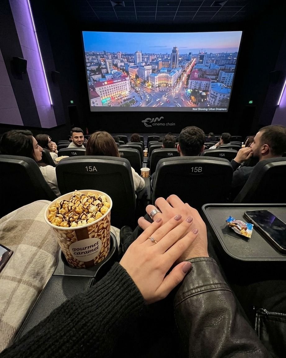 Couple holding hands with popcorn during a movie