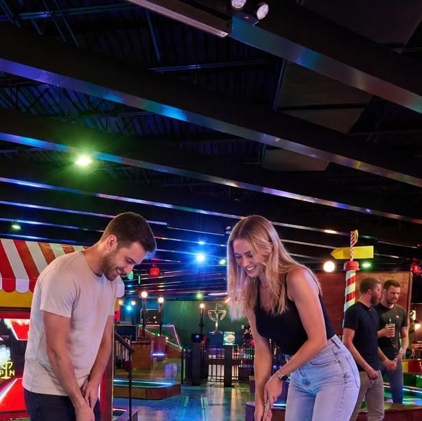 Couple playing mini golf together on a bright outdoor course
