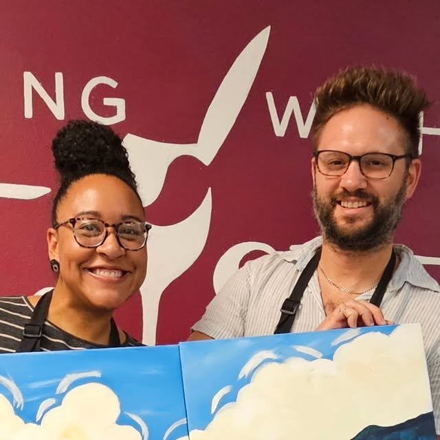 Couple showing off finished paintings after a paint date