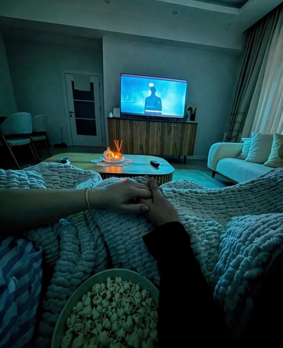 Couple relaxing on a candlelit couch with popcorn during a movie