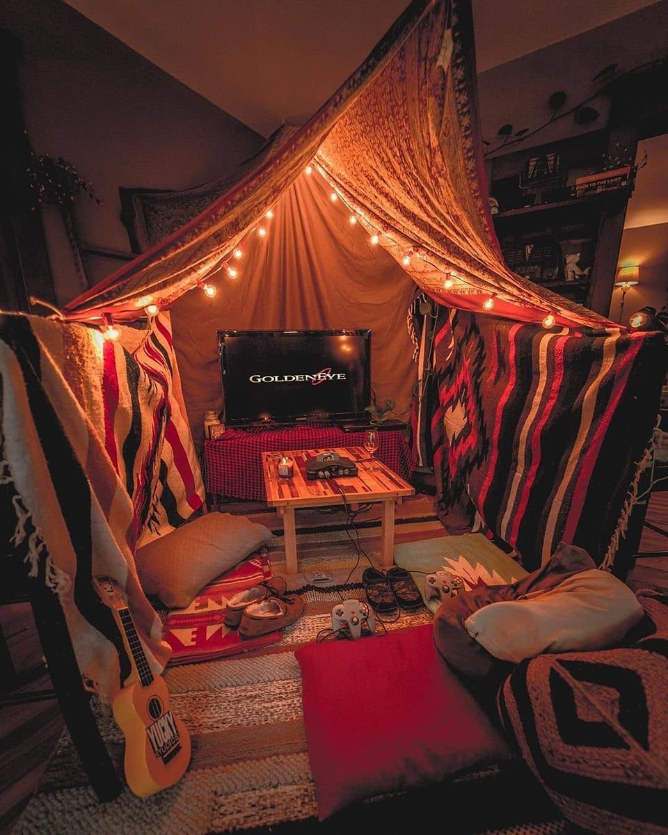 Blanket fort glowing with fairy lights and floor pillows