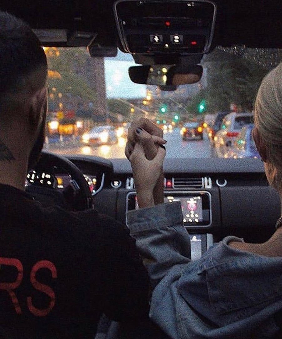 Couple holding hands on a night drive through the city