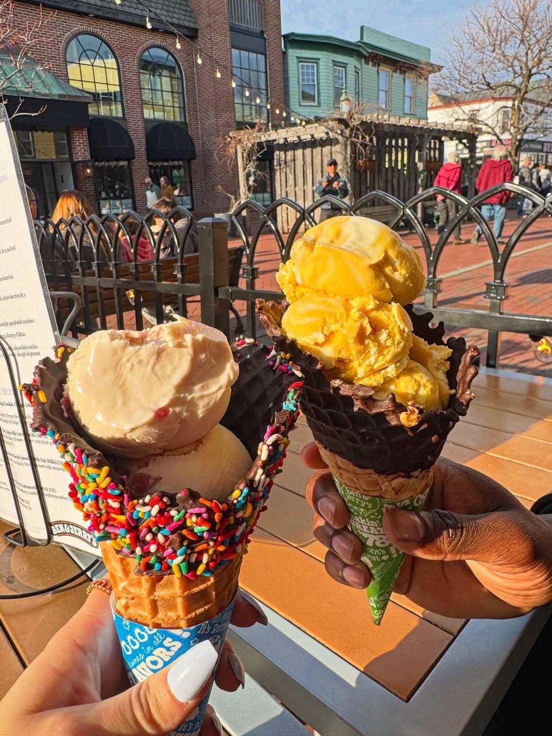 Two hands holding ice cream cones together at the beach