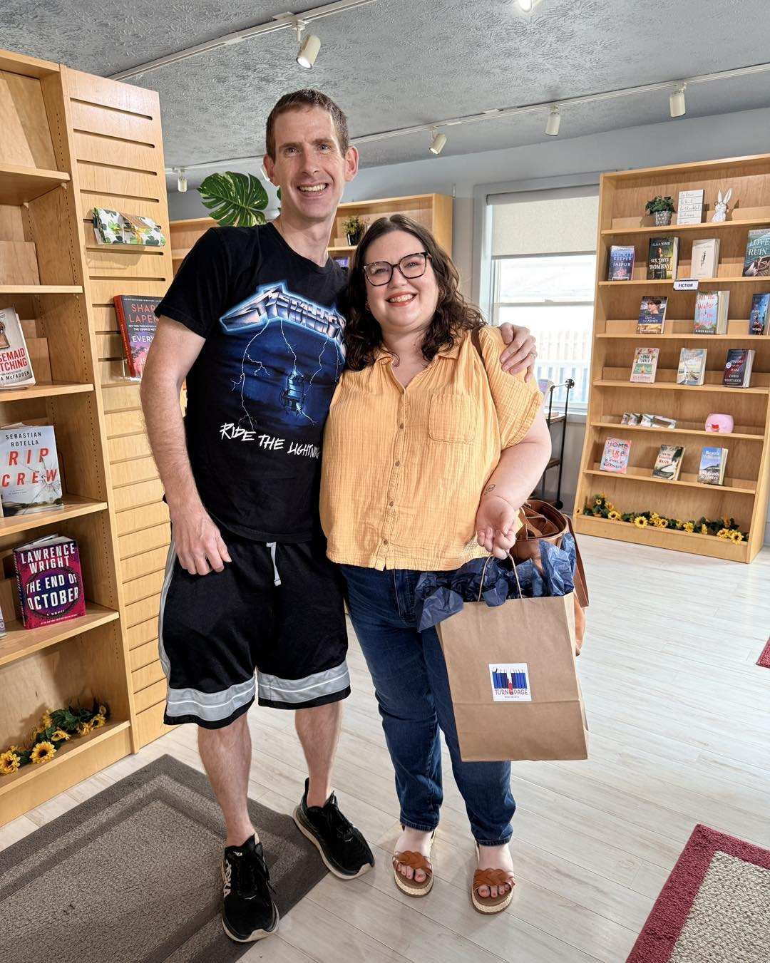 Married couple smiling in a bookstore with arms around each other