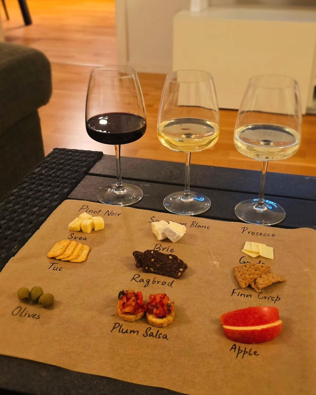 Three wine glasses with snack pairings on a home tasting table
