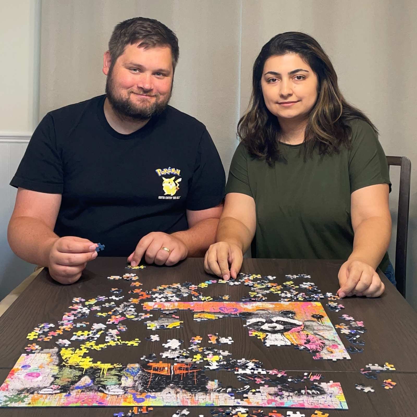 Smiling couple working on a colorful jigsaw puzzle at a table