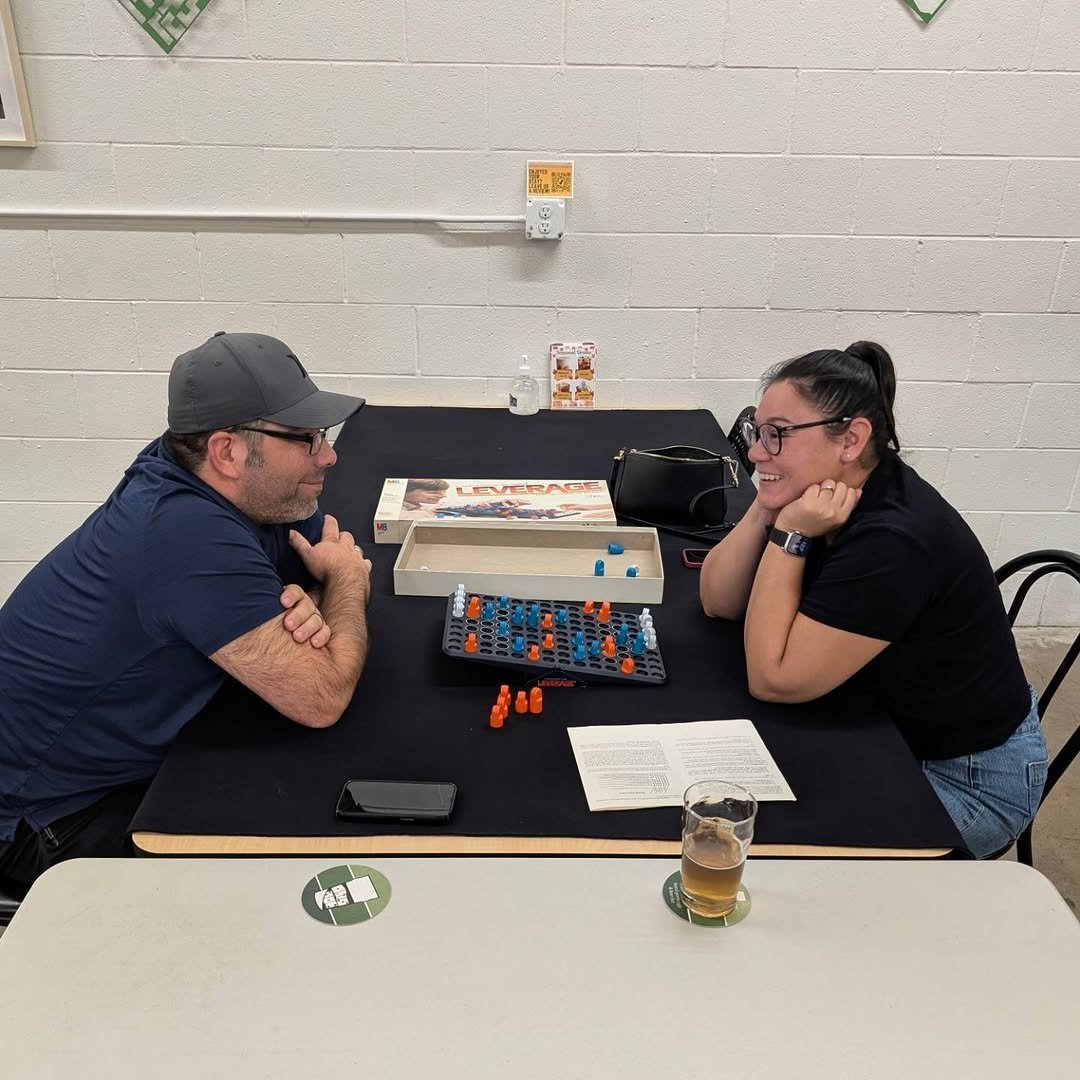 Man and woman playing a board game at a table with a beer