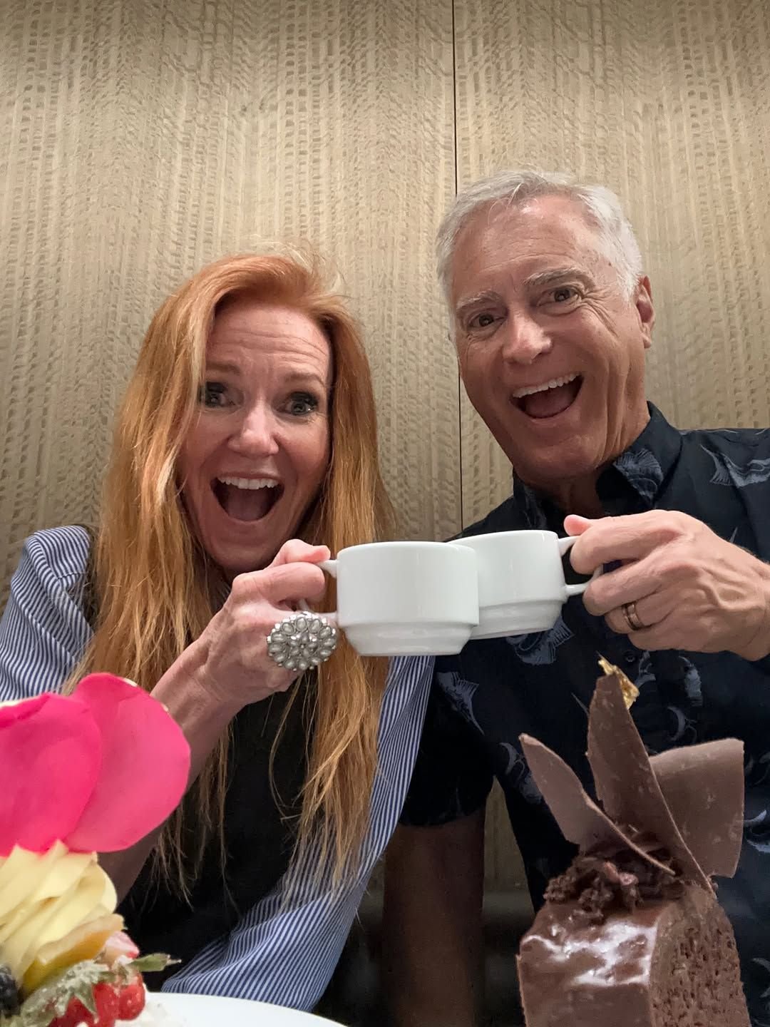 Happy couple toasting with mugs at a dessert cafe table