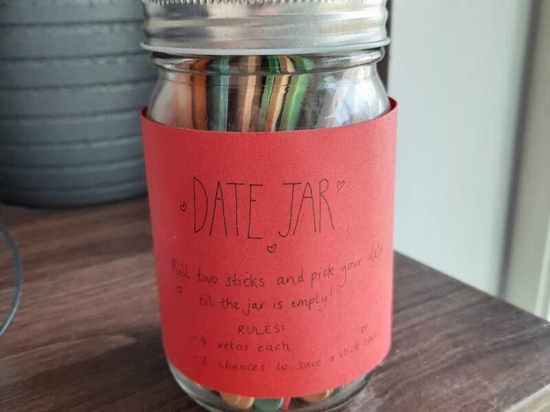 Decorated mason jar filled with colorful date night popsicle sticks