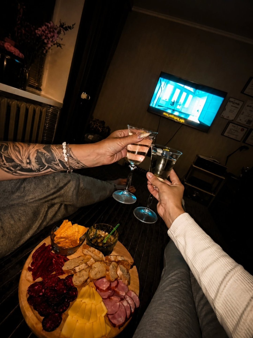 Couple toasting cocktails at a cozy at home movie date night