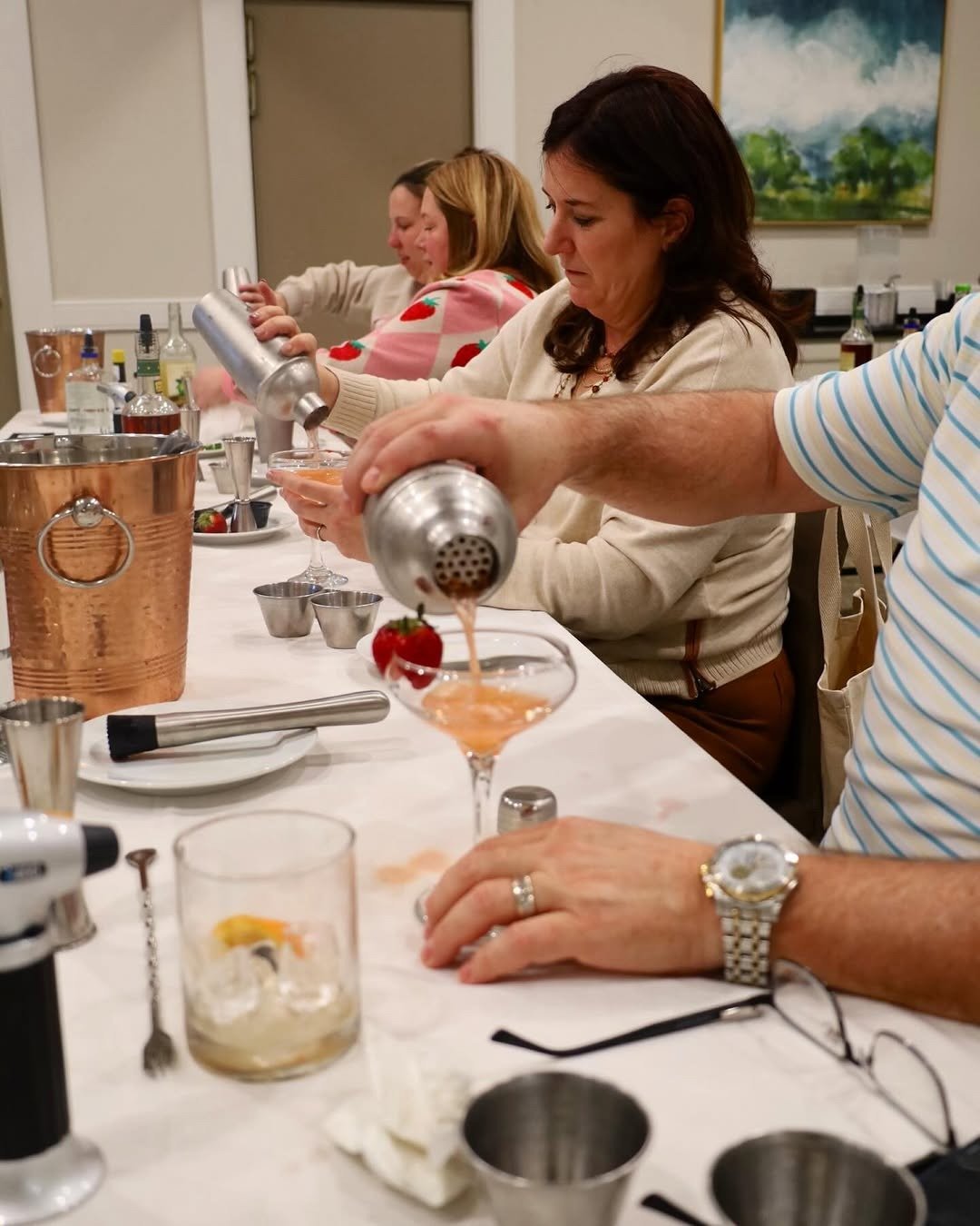 Cocktail class attendees shaking and straining drinks
