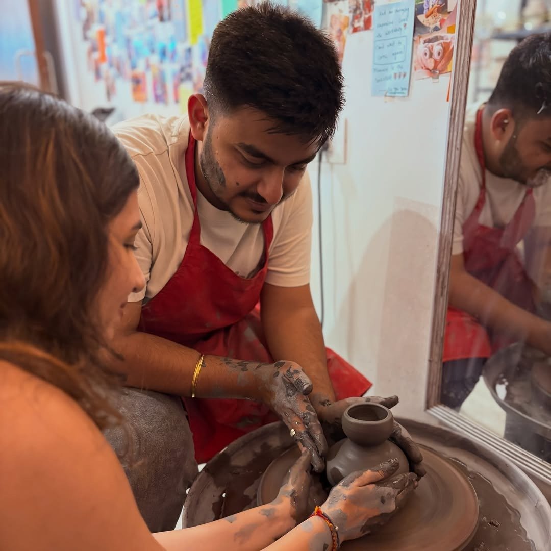 Couple shaping clay pot on pottery wheel