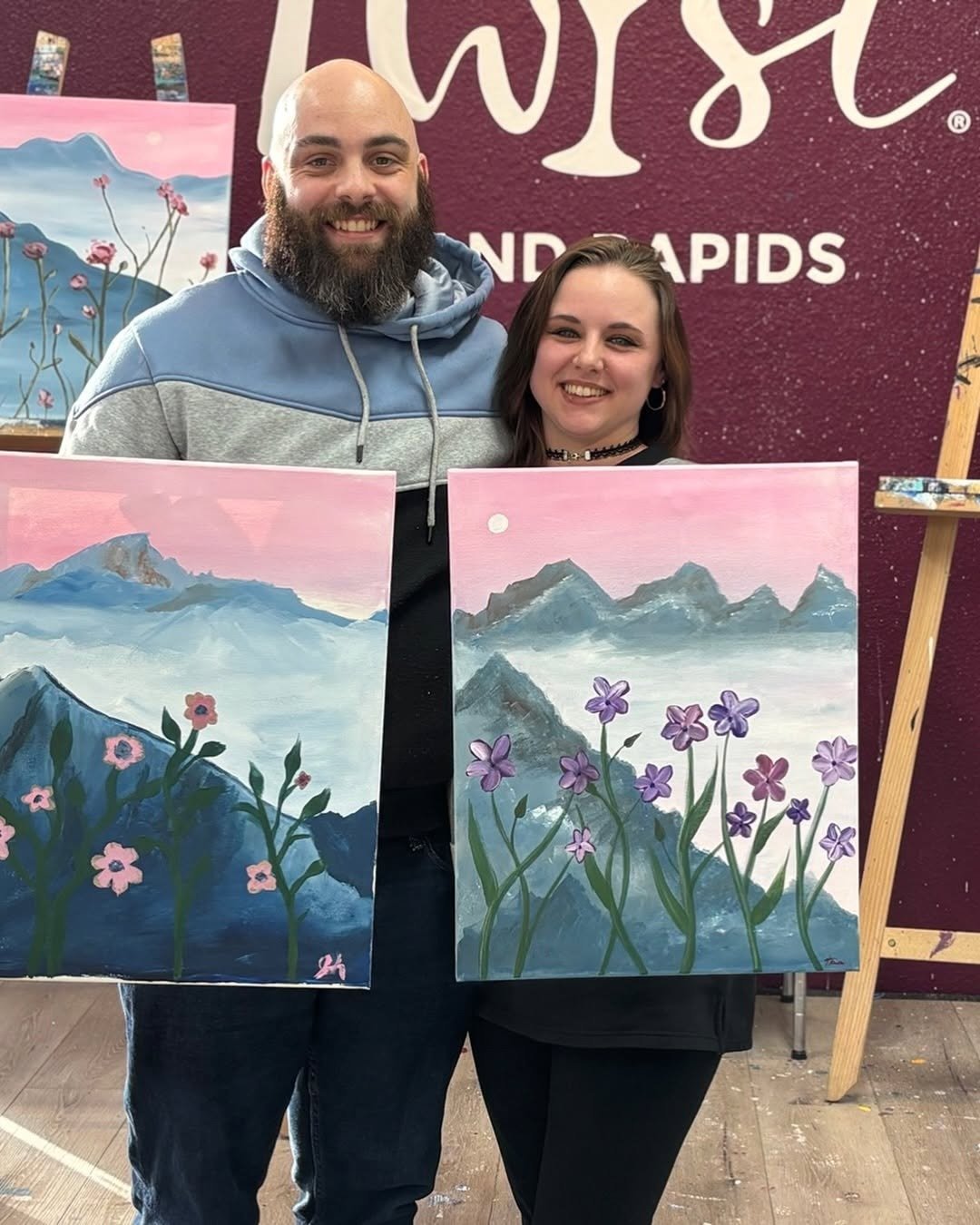 Couple holding finished paintings at paint studio