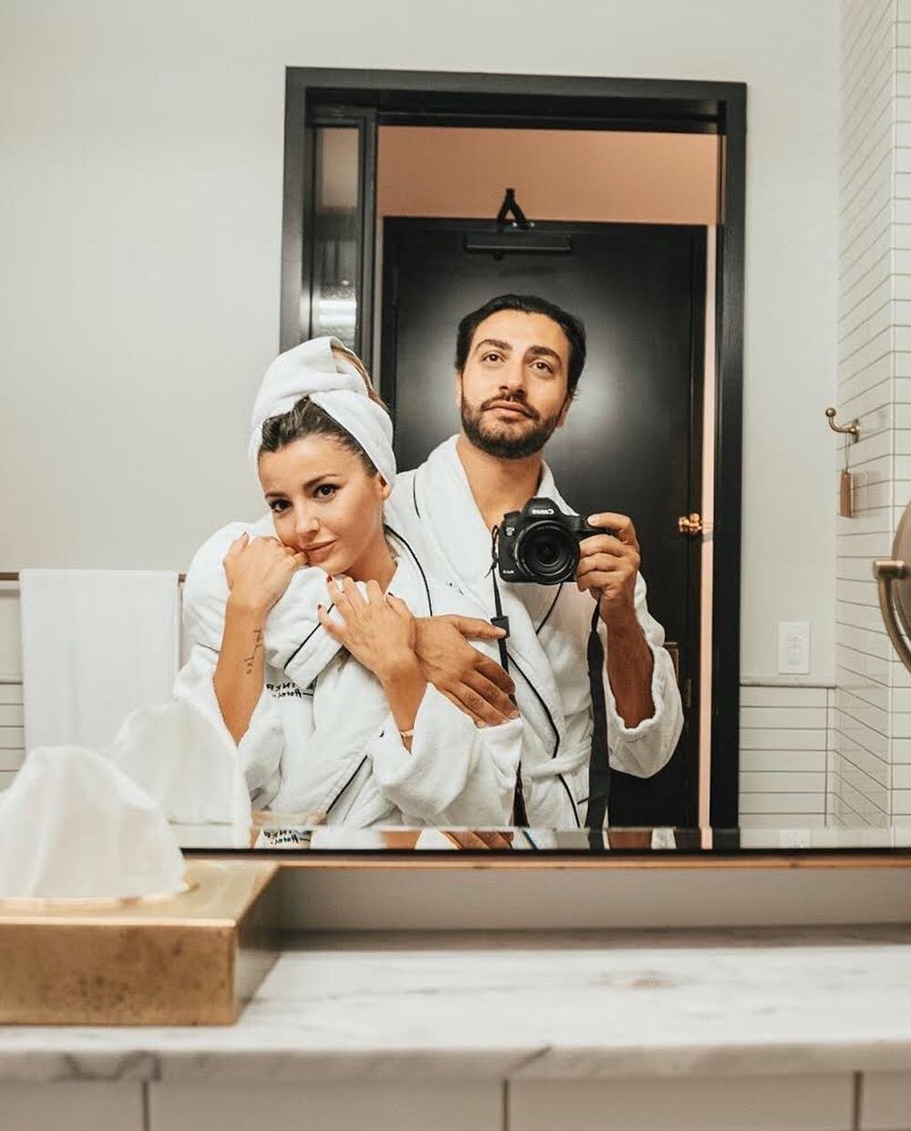 Couple in hotel bathrobes taking mirror selfie