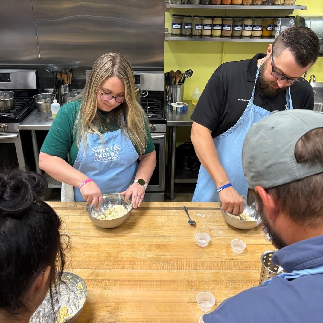 Couples in aprons mixing dough at cooking class
