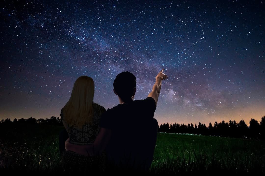 Couple sitting under star-filled night sky