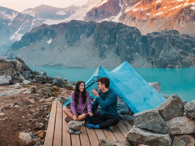 Couple laughing at alpine campsite by mountain lake