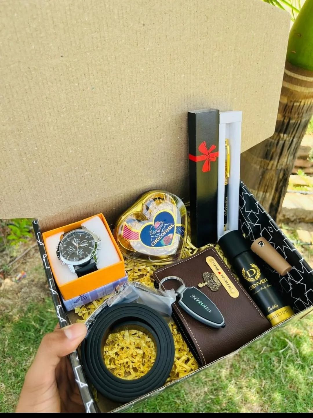 Open gift hamper with watch, wallet, pen set and chocolates