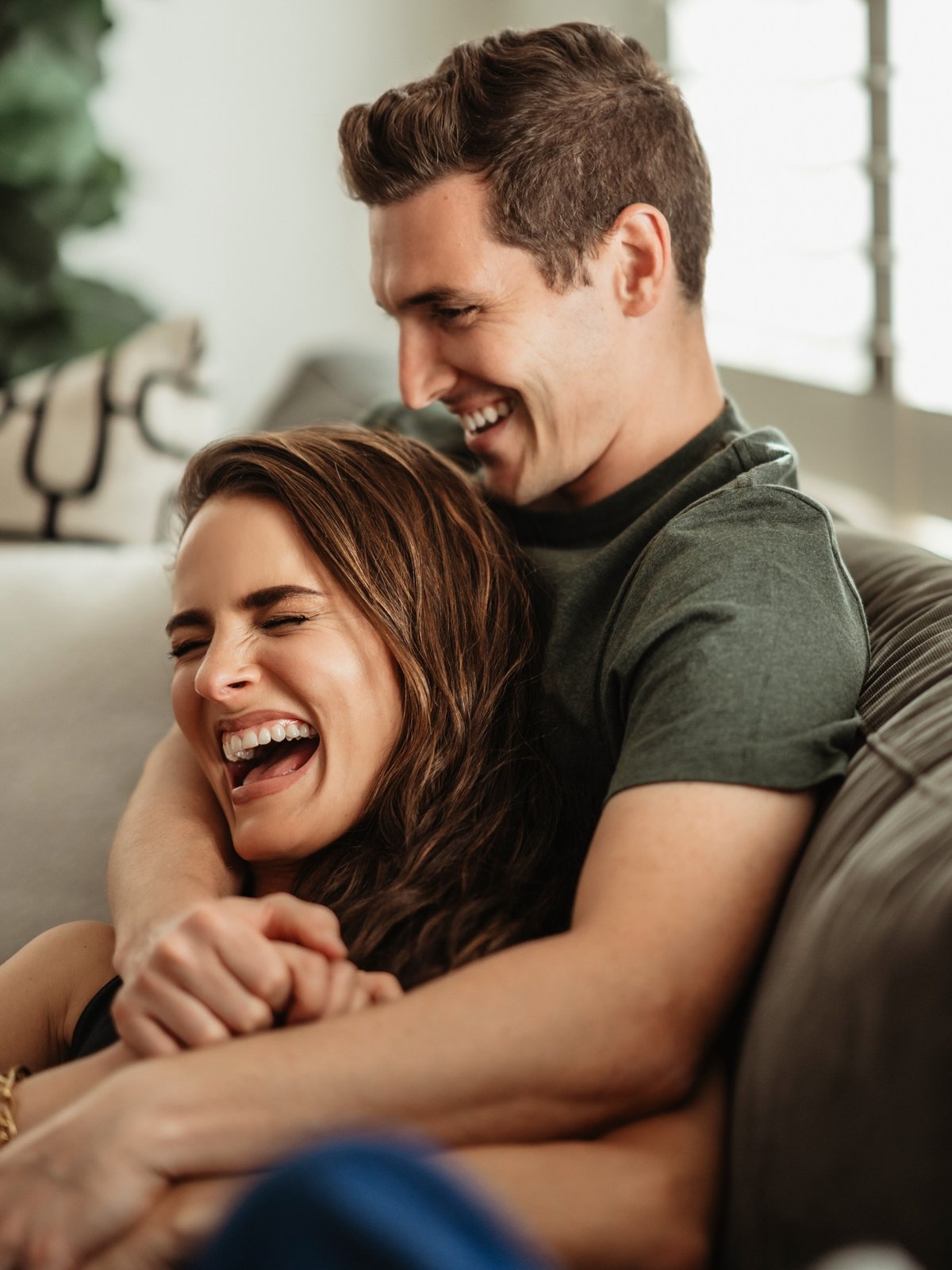 Couple laughing together on a couch at home
