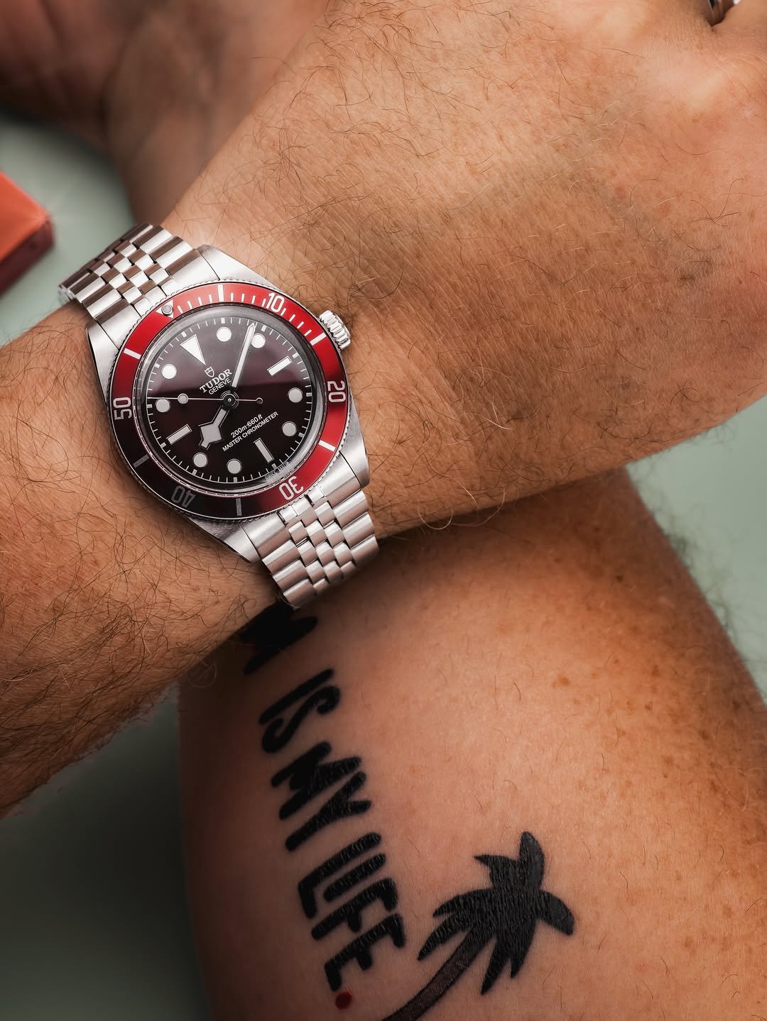Close-up of man's wrist wearing a burgundy bezel dive watch