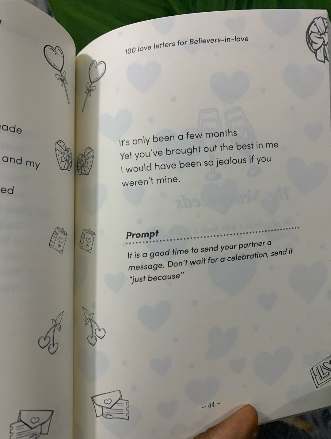 Hand holding an open fill-in love book with a prompt page