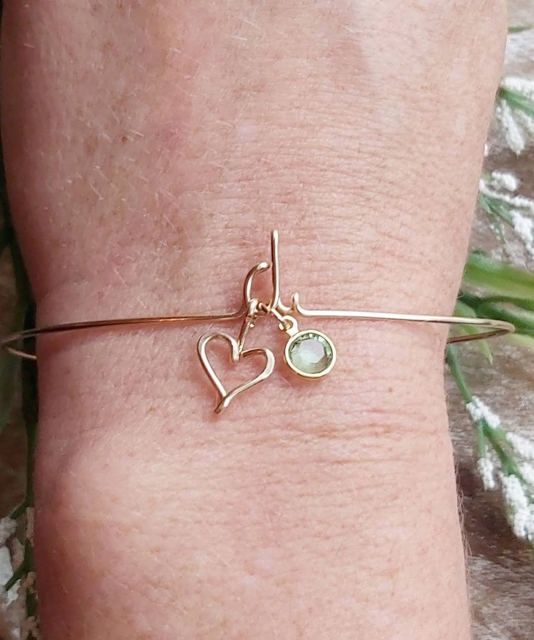 Gold bracelet with birthstone charm on wrist
