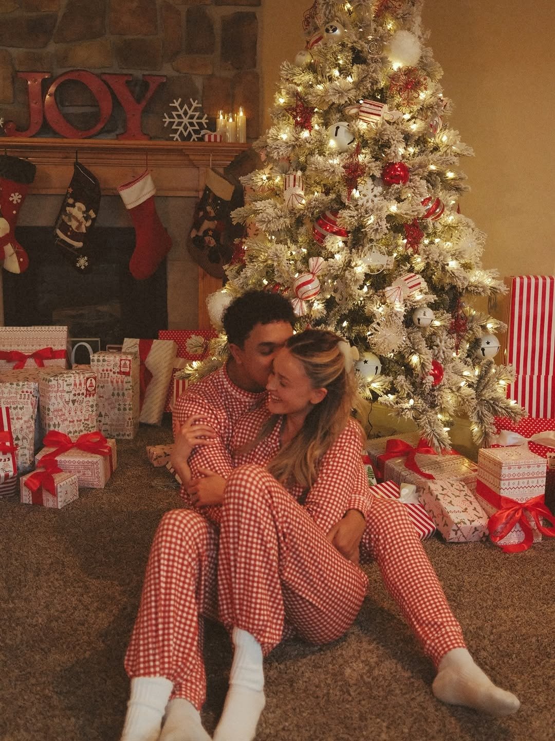 Couple in matching pyjamas by Christmas tree, from our handmade vs store-bought gifts guide