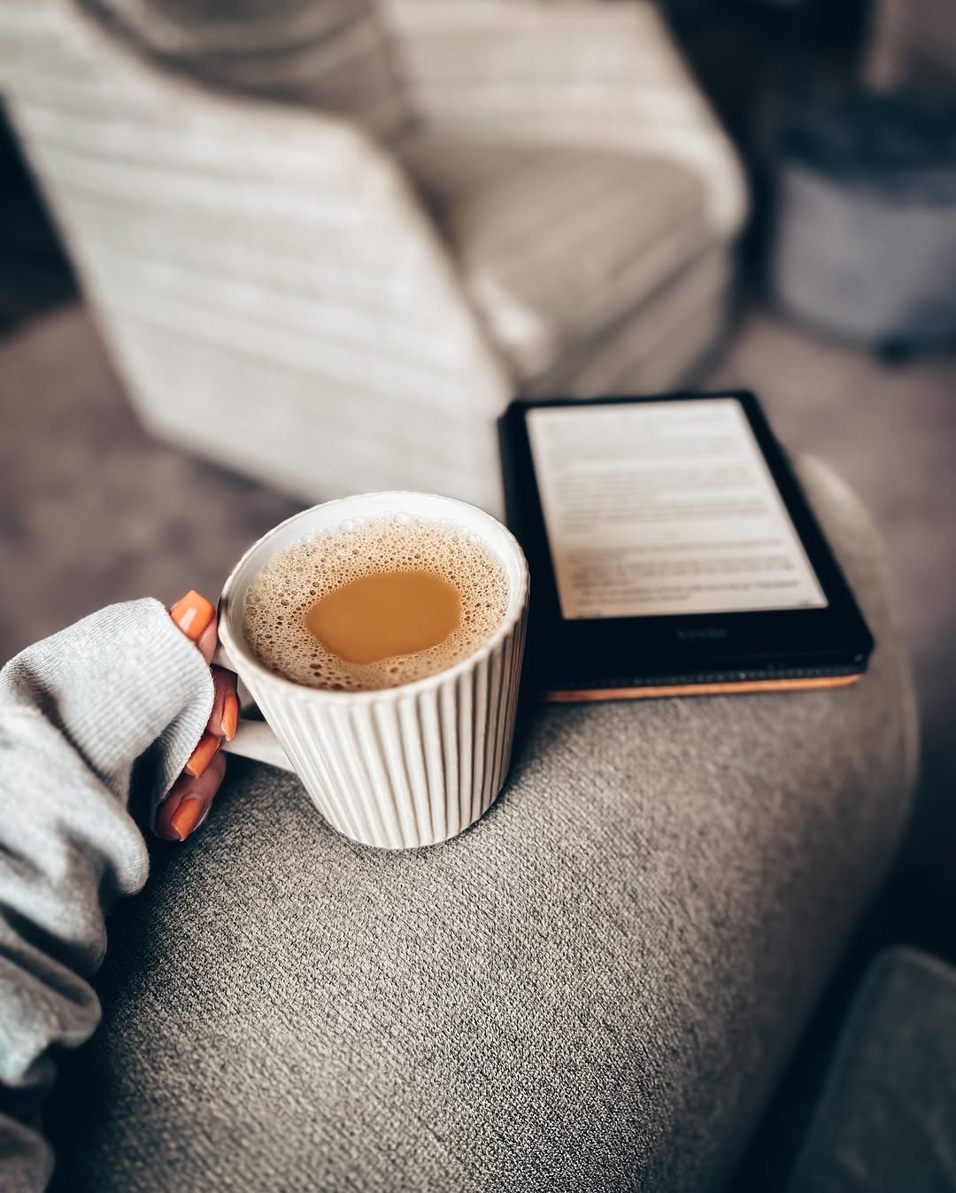 Kindle e-reader on sofa arm with coffee mug