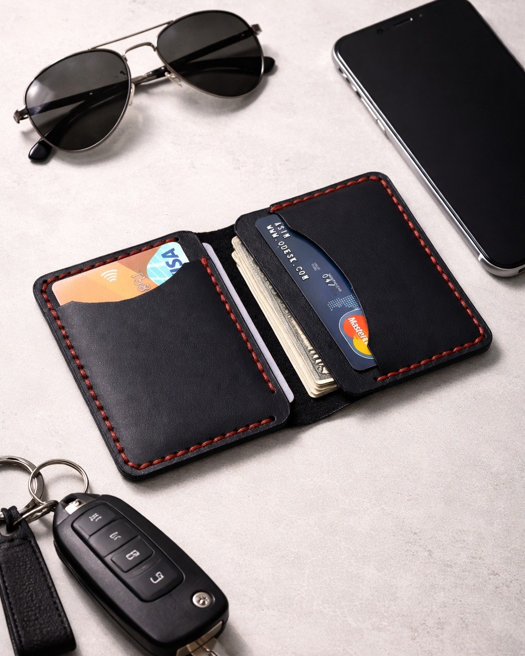 Slim black leather bifold wallet with sunglasses and keys