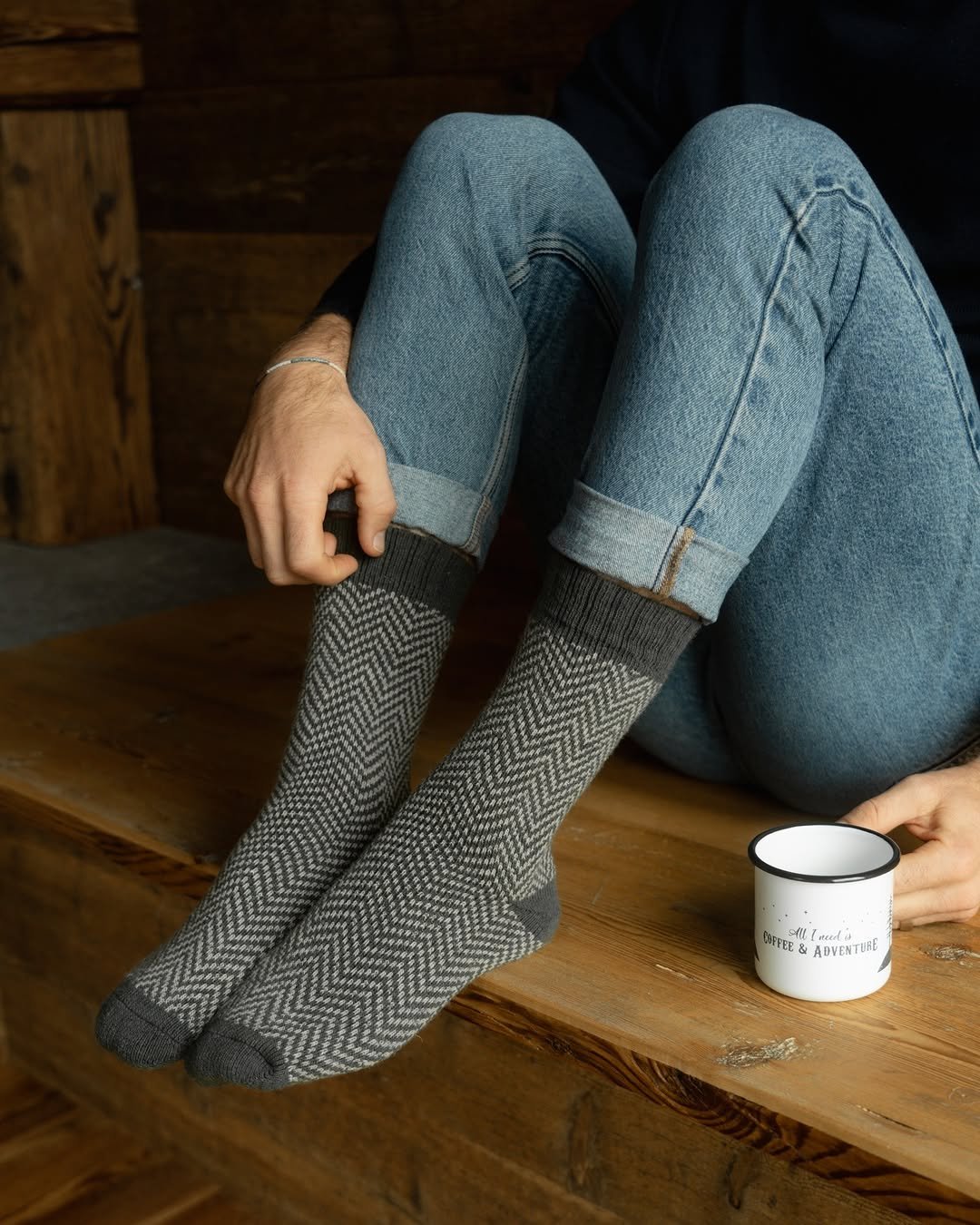 Man wearing grey wool crew socks on wooden bench