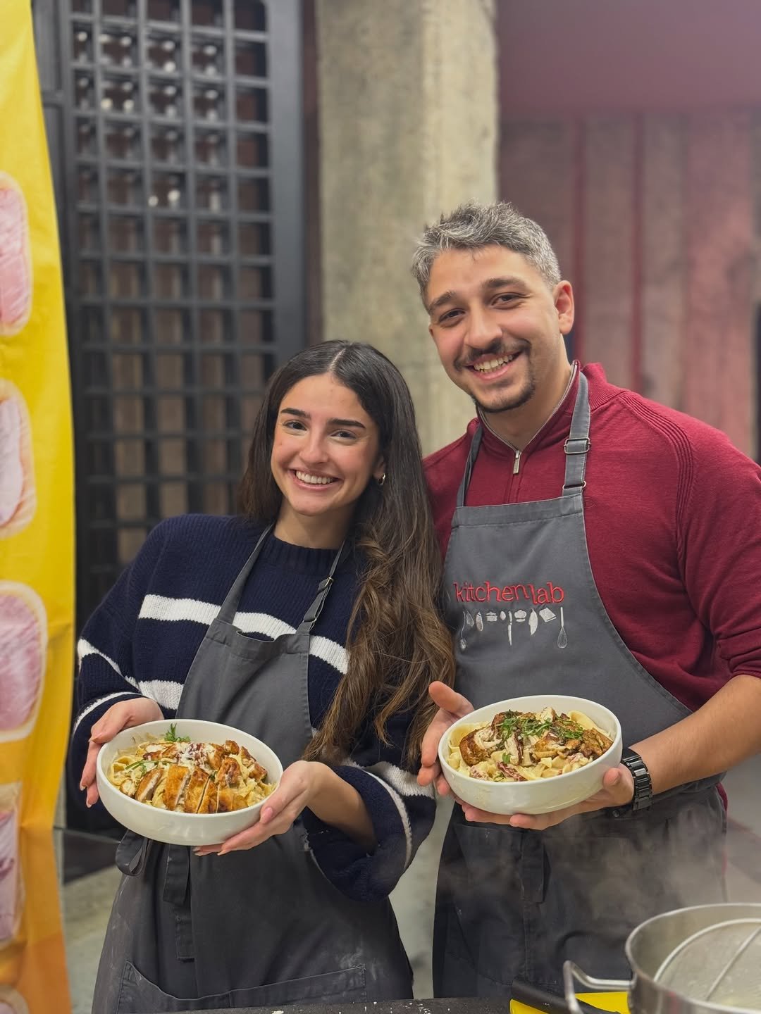 Couple in aprons holding dishes in cooking class