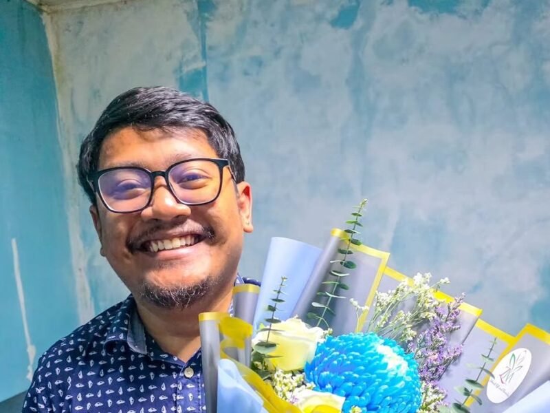 Smiling husband holding a wrapped bouquet gift from his wife