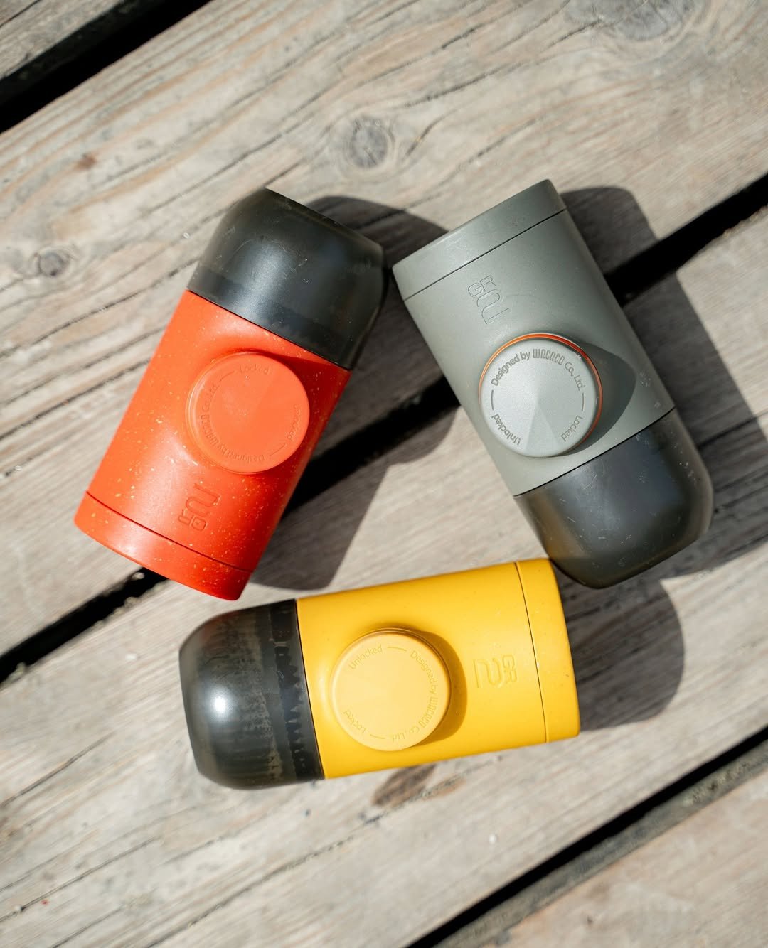 Three Wacaco Minipresso portable espresso makers on wooden surface