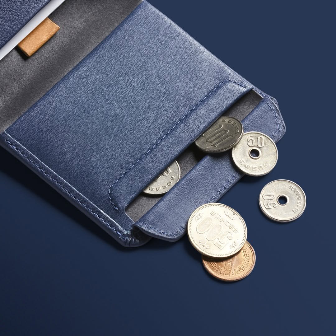 Blue Bellroy leather coin wallet with coins spilling out